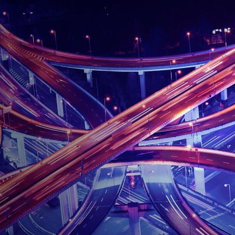 Aerial view of a brightly lit urban interchange at night, showcasing tangled highways.